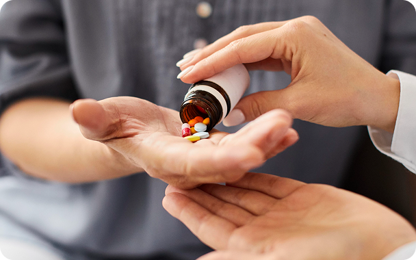 Close-up of a person pouring pills from a medication bottle