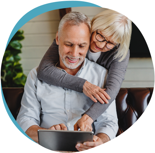 Older couple smiling while looking at a tablet together