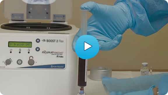 Technician loading a PRP tube into the BOOST 2 Flex centrifuge